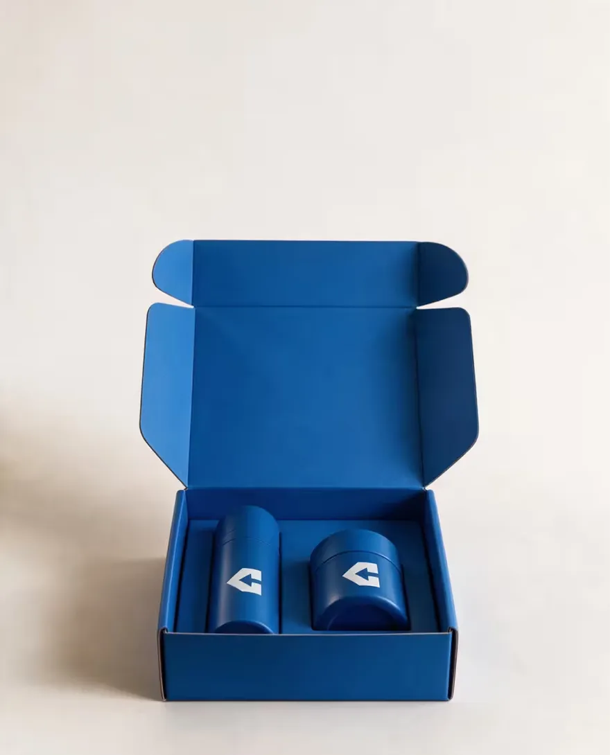 An open blue mailer box holding two bottles in a fitted insert.