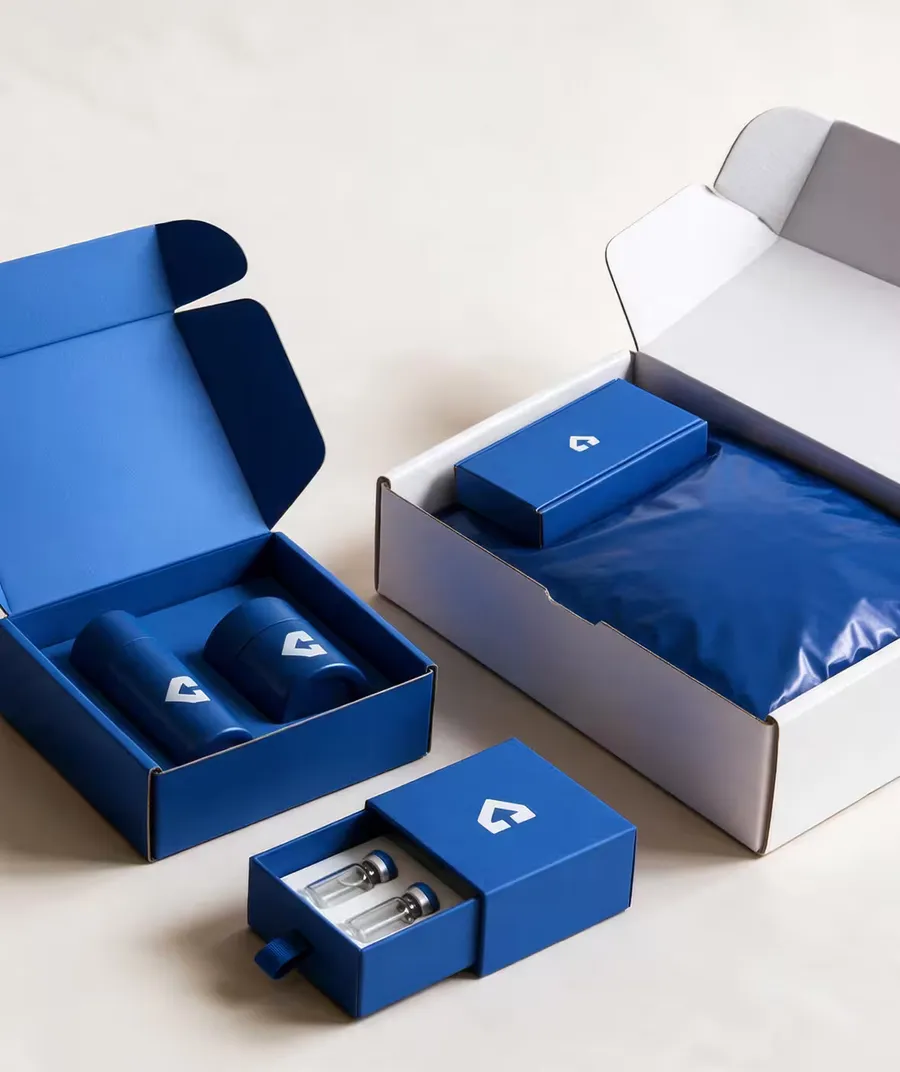A blue mailer box holding two bottles, a blue drawer box of vials, and a white mailer packed with a branded box and a blue pouch.