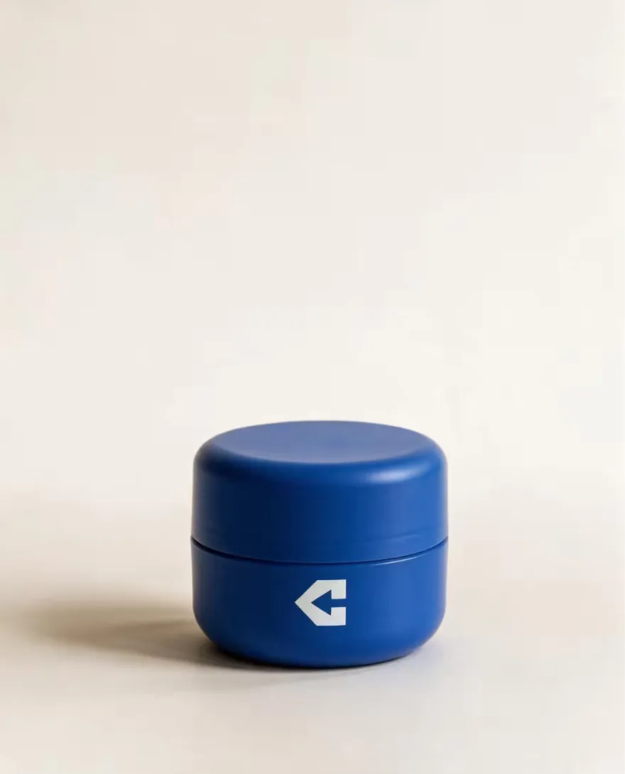 A closed navy wide-mouth ointment jar.