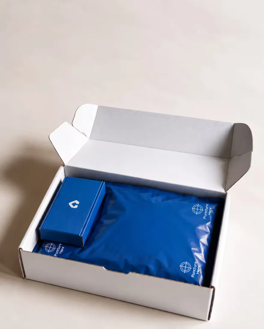 An open white corrugated mailer holding two branded boxes.