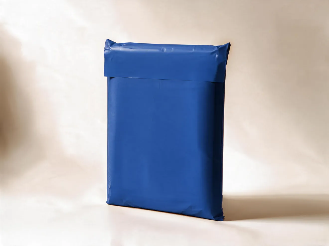An expanded navy PuncturePack mailer standing upright on a cream ground, its top flap folded over and sealed.