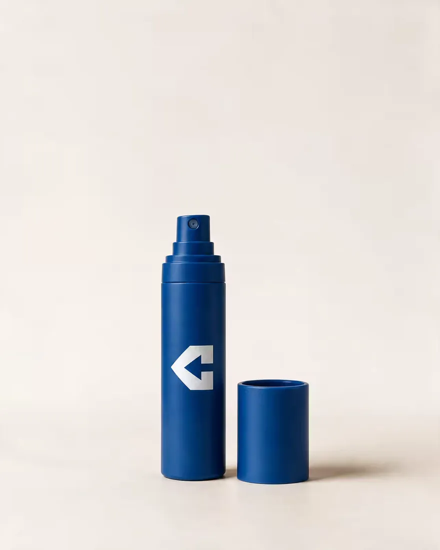 A navy spray bottle with its cap alongside.