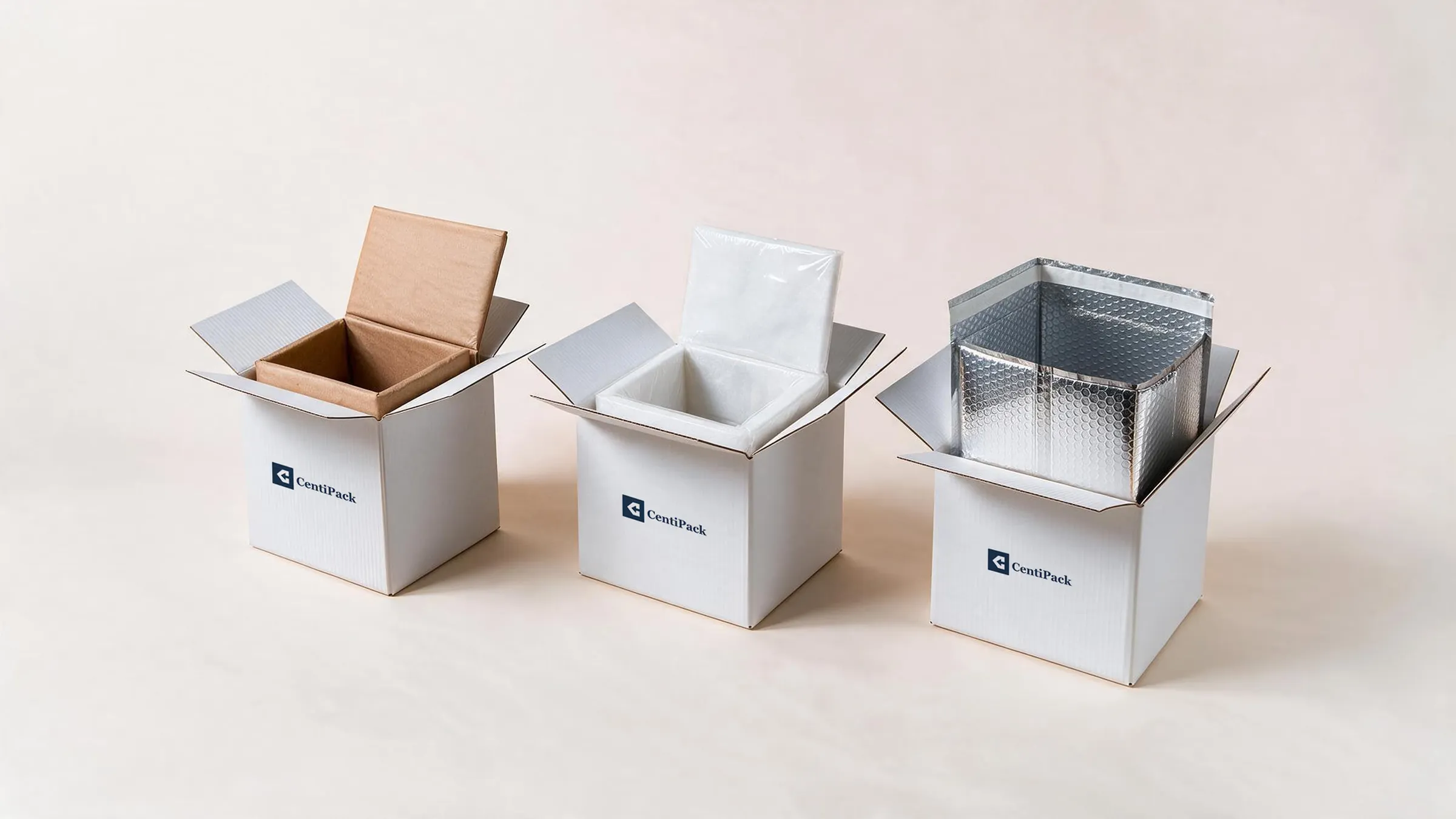 Three white CentiPack cartons side by side on a cream ground, each opened to show a different thermal liner — kraft paper, a white liner under clear film, and silver metallised bubble.